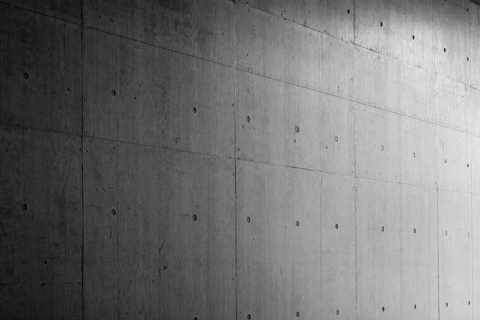 Black and white photograph of an in situ concrete wall carrying the board marks and sheet joints left by its plywood formwork