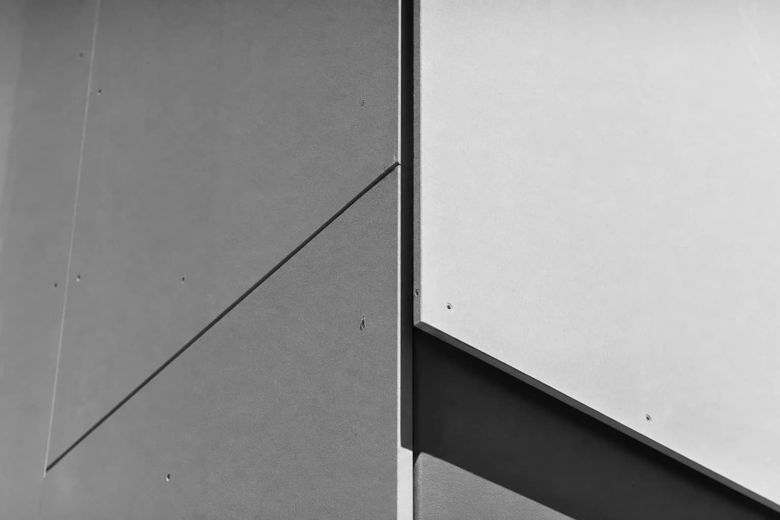 Black and white close detail of a crisp plasterwork wall junction and shadow line