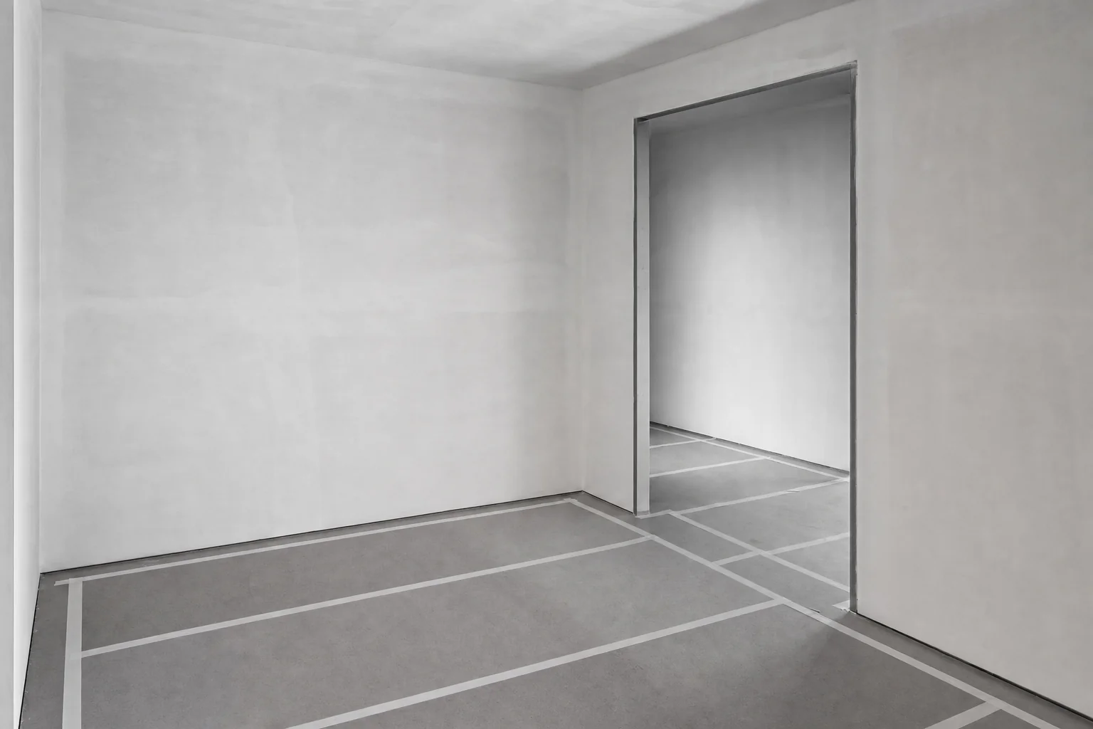 Black and white photograph of a domestic interior with the existing floor fully protected under taped sheeting mid-refurbishment