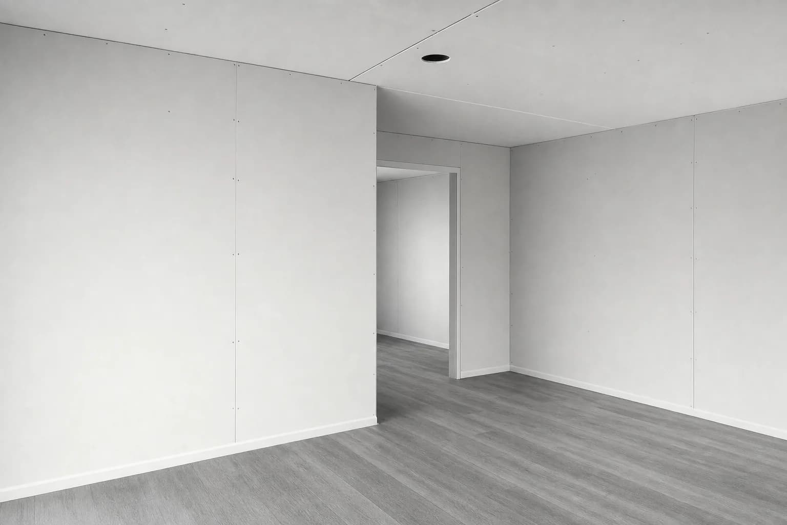 Black and white photograph of a transportable building interior during fitout, showing the jointed seam where two modules meet